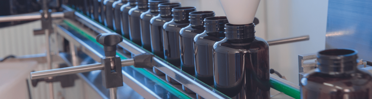 dark tablet or pill containers on a conveyor belt ready to be filled